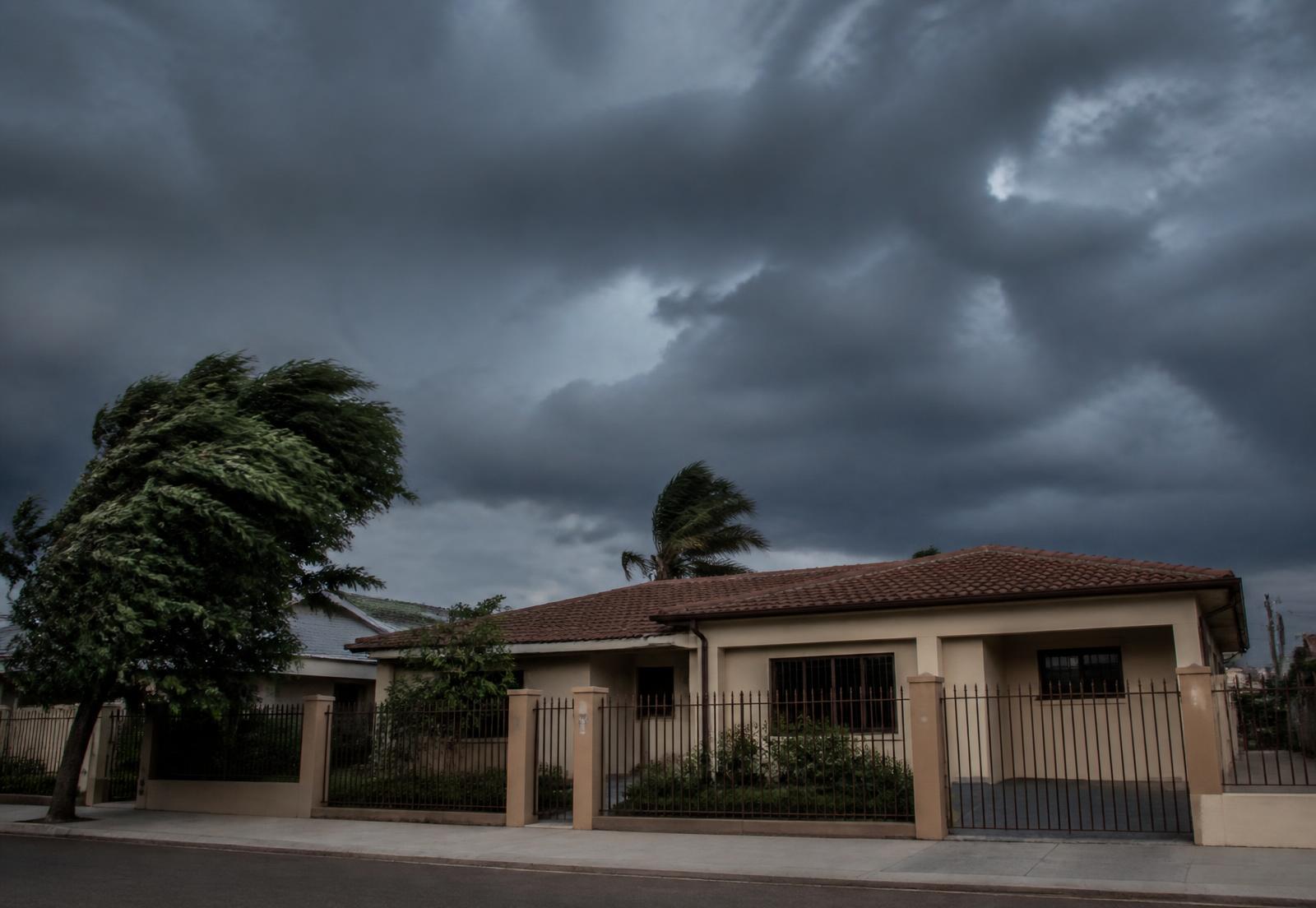 Casa térrea brasileira bem cuidada no fim da tarde, com céu carregado se aproximando